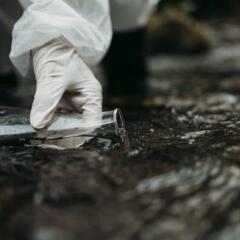 Close up shot of scientist biologist and researcher in protective suit taking water samples
