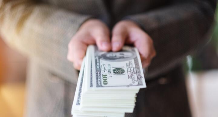 Closeup image of a woman holding and showing American dollar