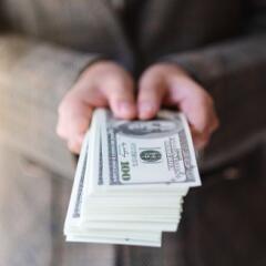 Closeup image of a woman holding and showing American dollar