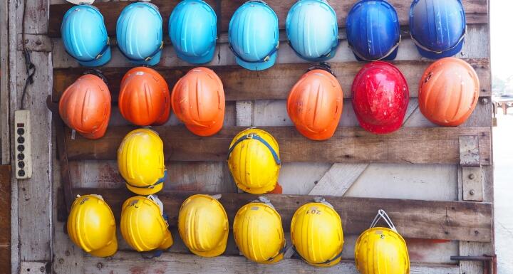 rows of colorful construction helmets hung on a wall