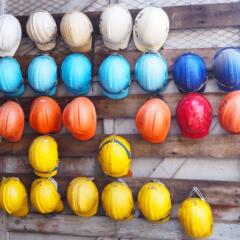rows of colorful construction helmets hung on a wall