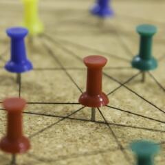 Colorful push pins connected by string on cork board