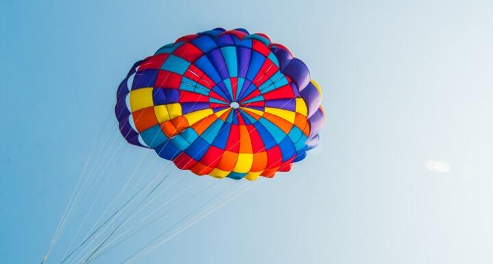 A colorful Rainbow striped parachute on a blue sky background