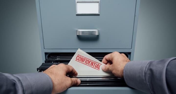 File labeled confidential being taken out of file cabinet