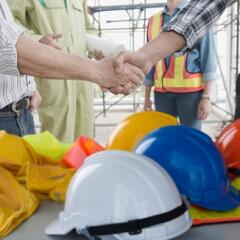 Construction group shaking hands with hardhats in foreground