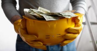 Construction hard hat filled with paper money