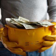 Construction hard hat filled with paper money