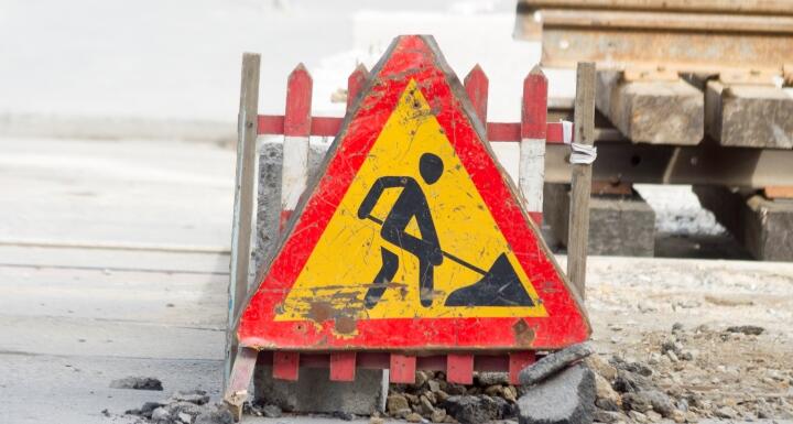 Construction utility sign on a cement pathway that is broken