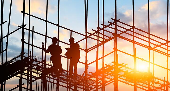Silhouette of construction workers on frame of building