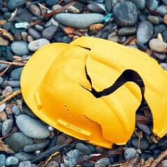 Cracked yellow construction helmet sitting on a bed of small stones