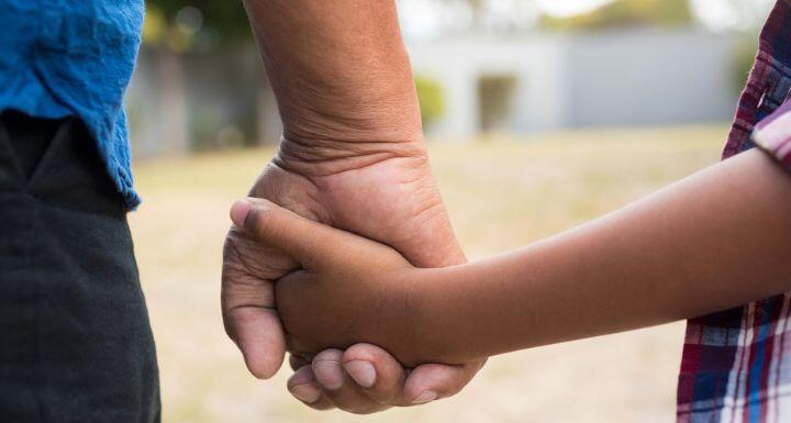 Cropped image of boy and grandfather holding hands