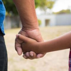 Cropped image of boy and grandfather holding hands