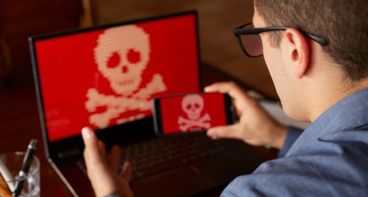 Man with a computer screen showing a potential computer virus and taking a photo of the computer with his phone