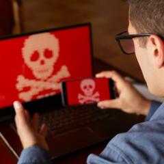 Man with a computer screen showing a potential computer virus and taking a photo of the computer with his phone