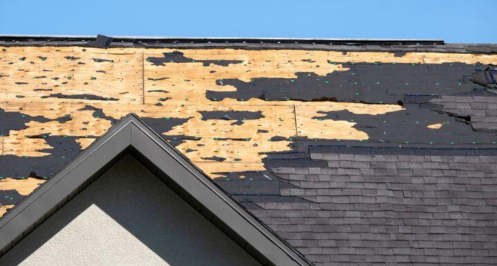 Damaged house roof with missing shingles