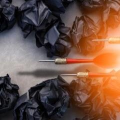 Red darts and black paper balls arranged on a grey background