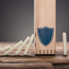 Wooden dominos falling into larger domino with blue shield