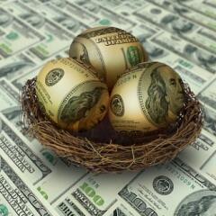 Egg shaped money in nest on top of hundred dollar bills