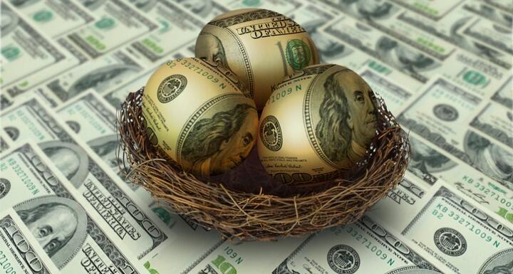 Egg shaped money in nest on top of hundred dollar bills