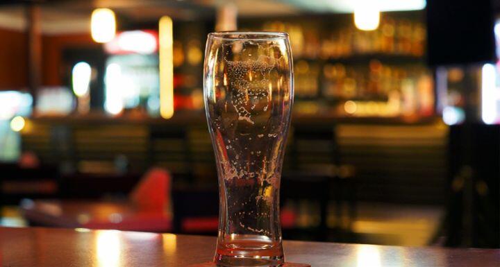 Empty beer glass on the table in a dark evening bar