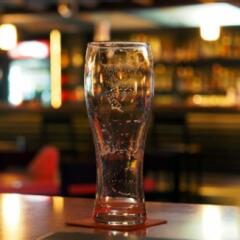 Empty beer glass on the table in a dark evening bar