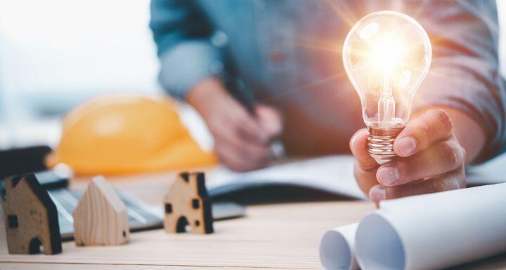 Engineers or architects holding Lightbulb and note on blueprint 