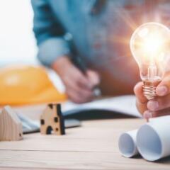 Engineers or architects holding Lightbulb and note on blueprint 