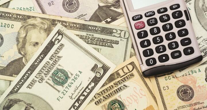 Layer of paper bills with a calculator resting on top