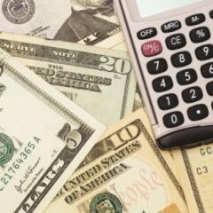 Layer of paper bills with a calculator resting on top
