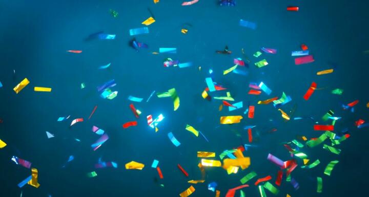 Falling multi-colored confetti on blue background