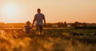 Father and son walking in field at sunset