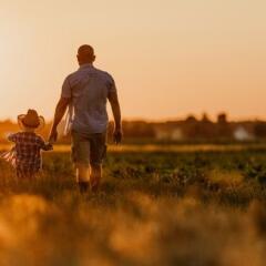 Father and son walking in field at sunset 