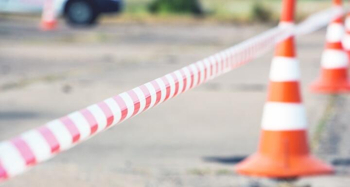 Orange construction cones and construction tape surround a lot