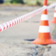 Orange construction cones and construction tape surround a lot