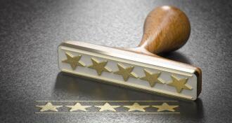 Five golden stars and a rubber stamp over black background