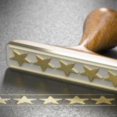 Five golden stars and a rubber stamp over black background