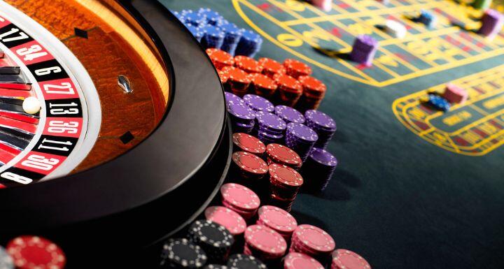 Gambling chips stacked around roulette wheel on gaming table