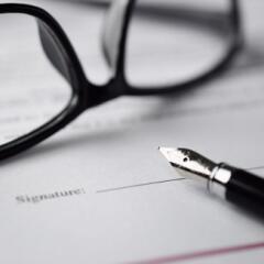 A pair of black glasses and fountain pen on top of a contract