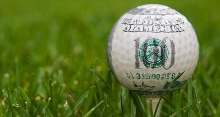 $100 bill printed on white golf ball sitting on tee