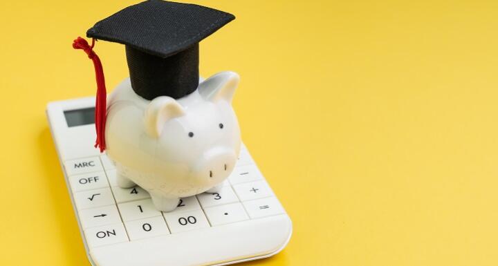 Illustration of a piggy bank wearing a graduation cap and tassel on top of a calculator