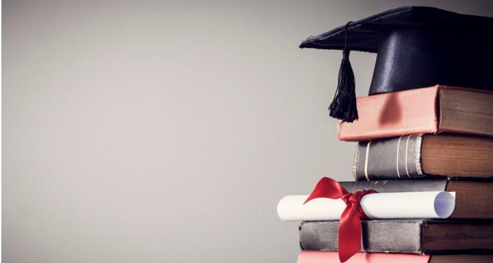 Graduation cap sitting on books and diploma