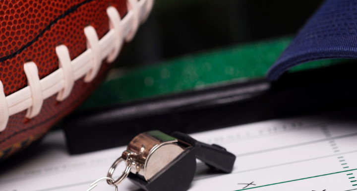 A football and whistle on a play sheet