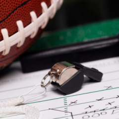 A football and whistle on a play sheet