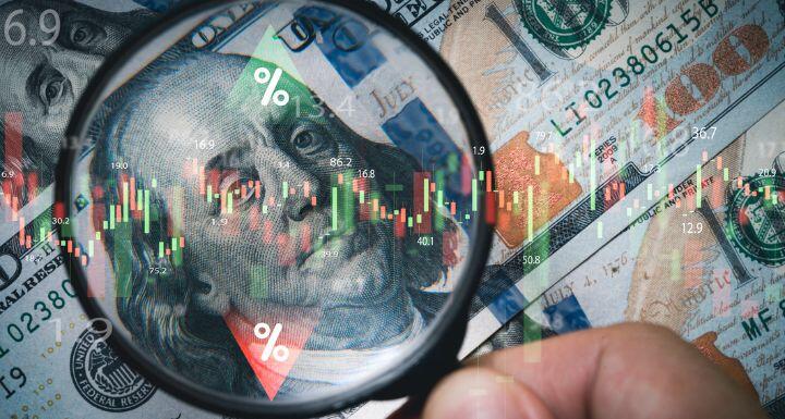 Hand holding magnifier glass to focus Benjamin Franklin face on USD dollar 