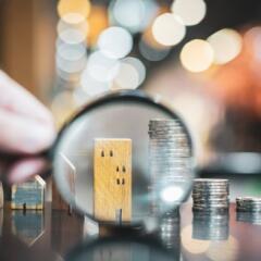 Hand holding magnifying glass and looking at building
