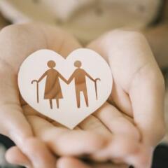 Hand holding paper cutout of elderly couple