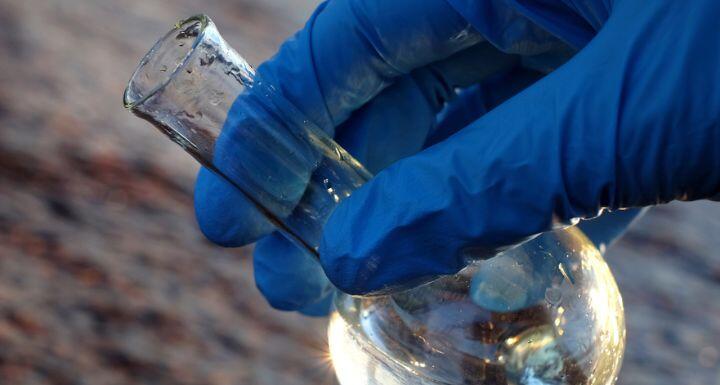 Hand in glove holding water sample