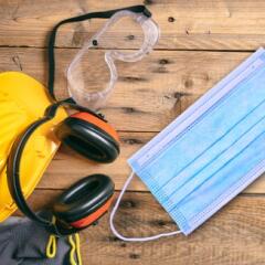 Hard hat, construction safety accessories, and protective mask on top of wood table