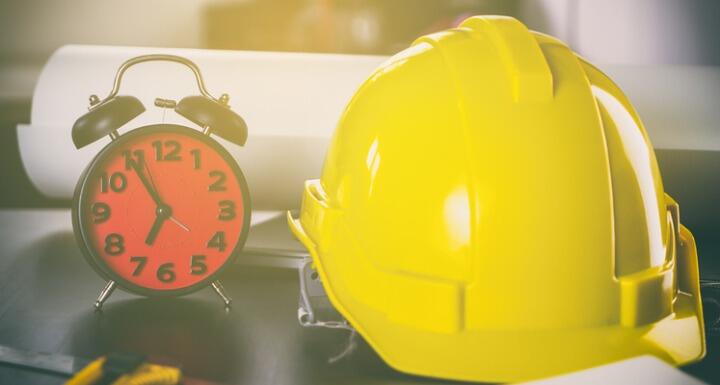 Yellow hard hat and alarm clock sitting on desk