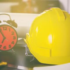 Yellow hard hat and alarm clock sitting on desk